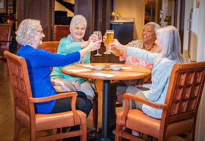 Residents toasting with drinks at a communal table