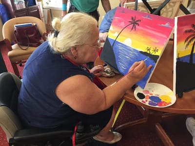 Resident painting a sunset on a canvas