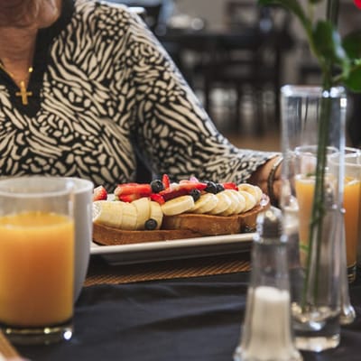 A resident enjoying a dessert with fruit in a dining area
