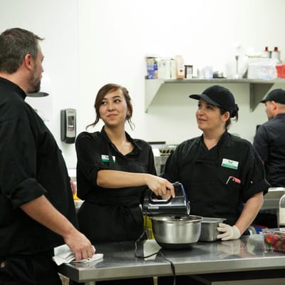 Staff preparing food in a kitchen with smiling expressions