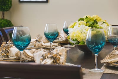 A beautifully set dining table with colored glasses and flowers