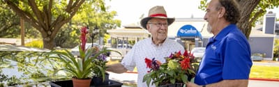 Two men exchanging potted flowers outdoors