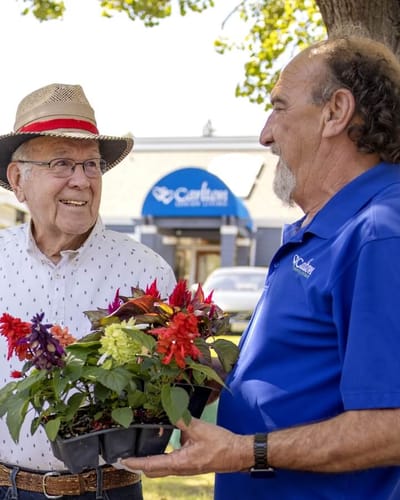A resident and staff member chatting outdoors with flowers