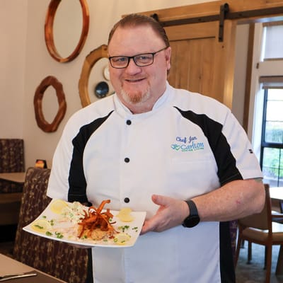 Chef presenting a gourmet dish in the dining area