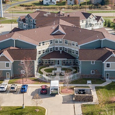 Aerial view of a senior living facility with gardens and parking