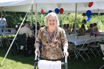 A resident smiling at an outdoor event with tables and decorations