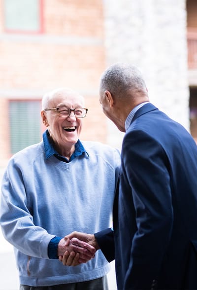 A resident and staff member sharing a friendly handshake.