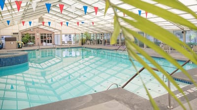 Indoor swimming pool area with a clear roof and lounge chairs