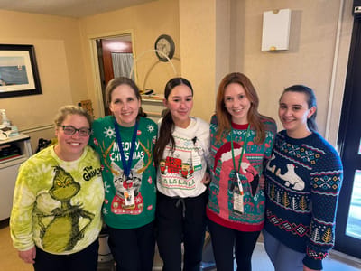 Staff members in festive holiday sweaters posing together