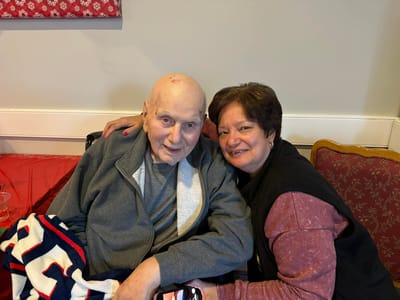 A resident and staff member posing together in a common area