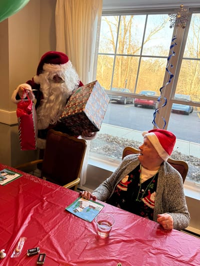 Resident receiving a gift from Santa during a holiday event