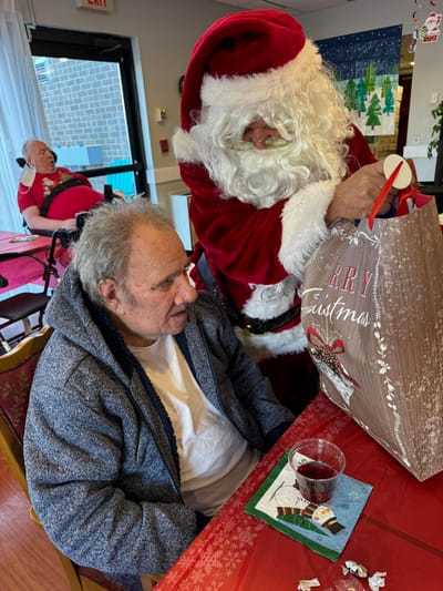 Resident receiving a gift from Santa during a celebration