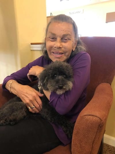 A resident smiling and holding a dog.