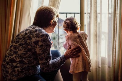 Elderly woman and child looking out a window.