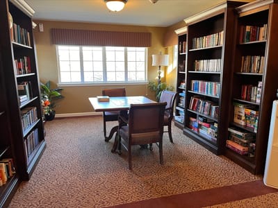 A cozy common area with bookshelves and a table