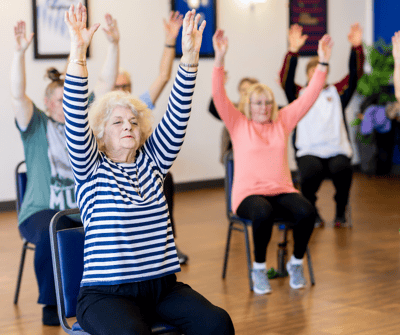 Seniors engaged in a seated exercise class