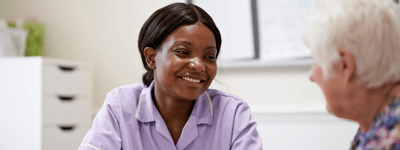 Caregiver smiling while talking to a resident.