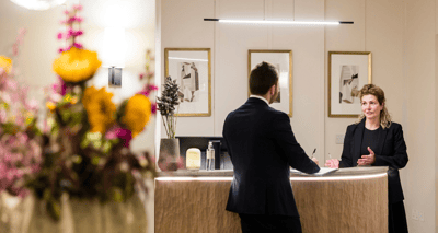 Staff member assisting a visitor at reception.