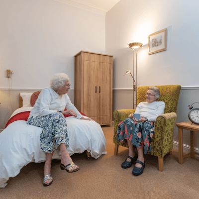 Two elderly women chatting in a cozy room.