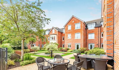 A garden area with tables and brick buildings.