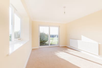 Bright, empty room with carpet and sliding doors.