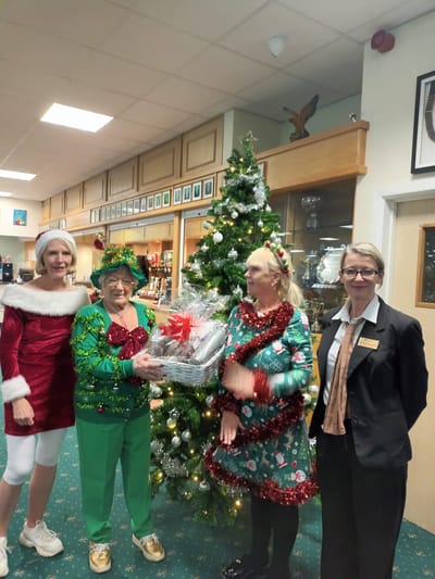 Residents and staff celebrating around a Christmas tree