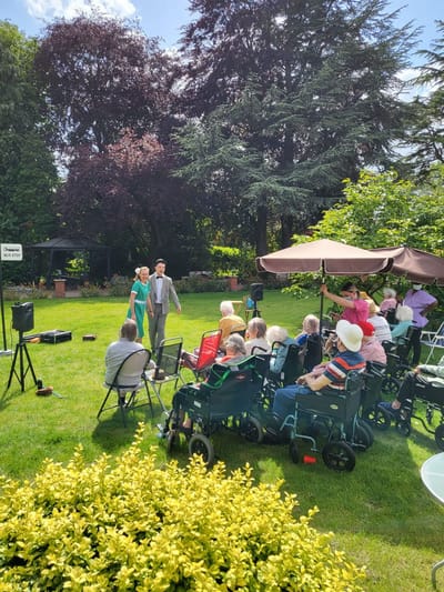 Residents enjoying an outdoor performance at the facility.