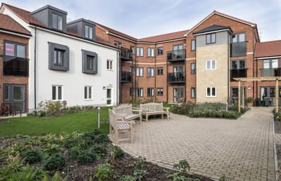 Exterior view of a retirement living facility with gardens