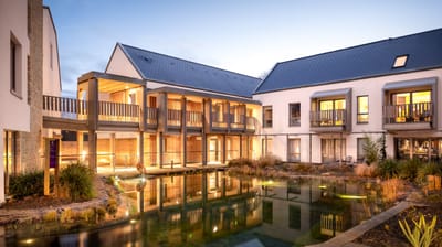Modern building exterior with outdoor space and pond.