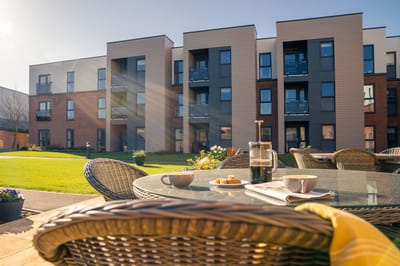 Outdoor seating area with breakfast items and the building behind.