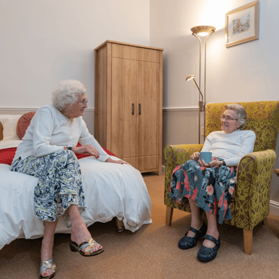 Two senior women chatting in a cozy room.