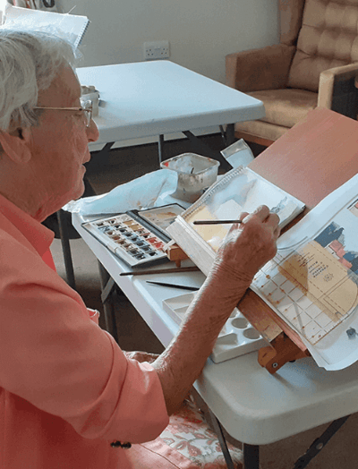 Senior resident painting at a table