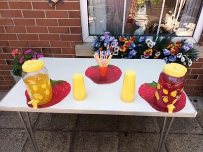 Colorful beverage setup with drinks and cups outside
