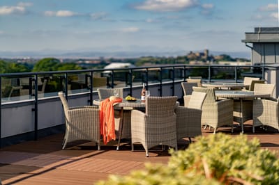 Rooftop terrace with wicker furniture and scenic view.