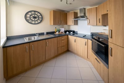 Modern kitchen with wooden cabinets and clock.