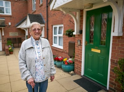 Elderly woman standing outside a green door