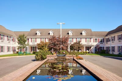 Exterior view of a senior living facility courtyard with a pond