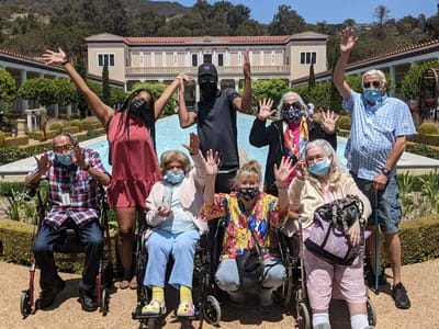 Residents and staff celebrating outdoors with raised hands