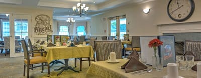 Dining room set up for meals with flowers on tables