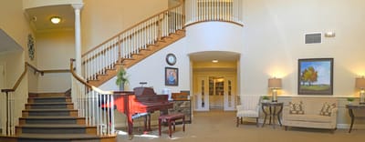 Bright interior of a common area with a piano and seating