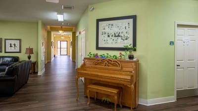 Interior view of a hallway with a piano and artwork