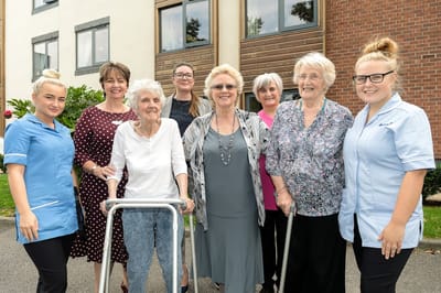 Residents and staff smiling outside the care home