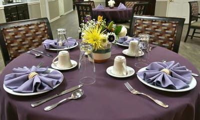 Dining table set with flowers and purple napkins
