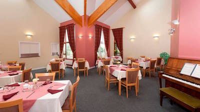 Dining room with neatly set tables and a piano
