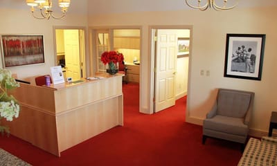 A well-lit reception area with red carpeting and flowers