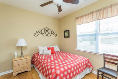 A cozy resident room with a red patterned bedspread