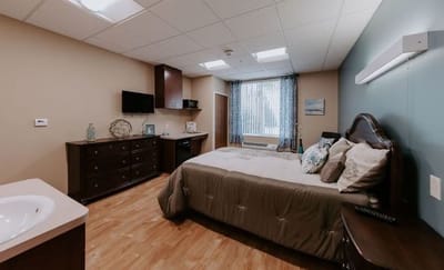 A cozy private resident room with a bed and dresser