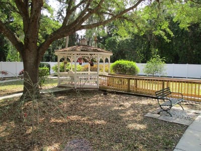 Outdoor gazebo area with a bench and greenery