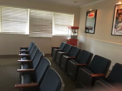 A cozy interior waiting room with blue chairs and a popcorn machine