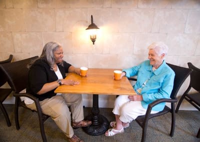 Two seniors enjoying conversation over coffee at a table